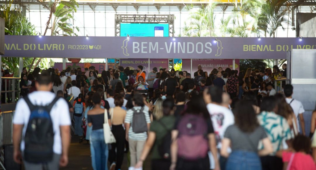 Em um dia de sol, pessoas entrando na Bienal do Livro Rio com árvores ao redor