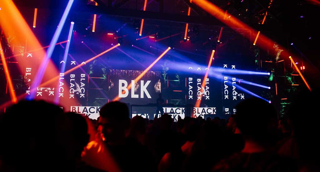 Palco da festa Black com pessoas assistindo, luzes coloridas e telões de led