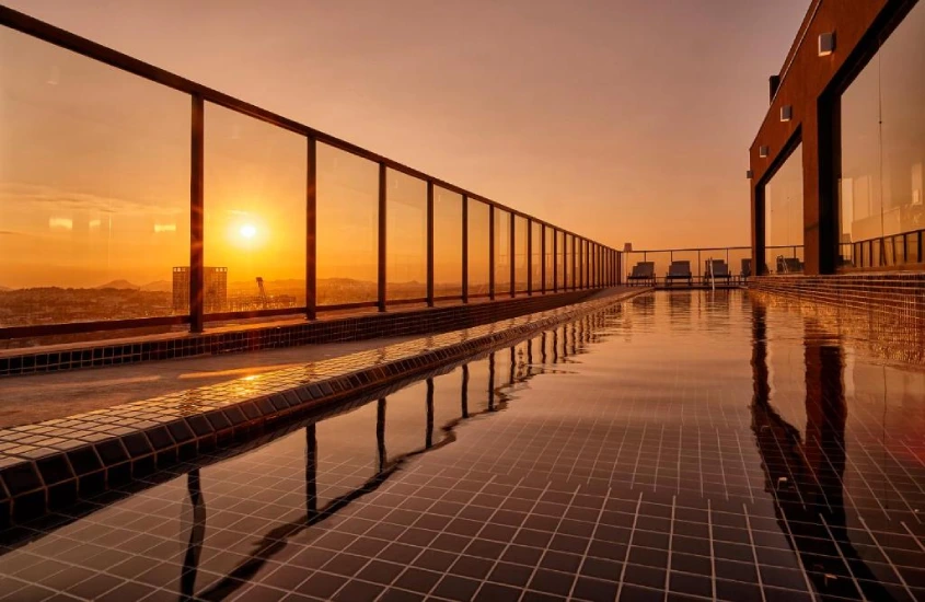 Durante o pôr do sol, área de cobertura com piscina e paisagem do mar