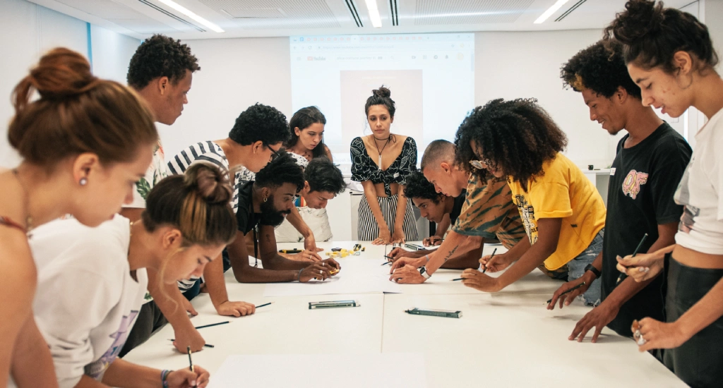 Pessoas em sala de reuniões em pé ao redor de uma mesa