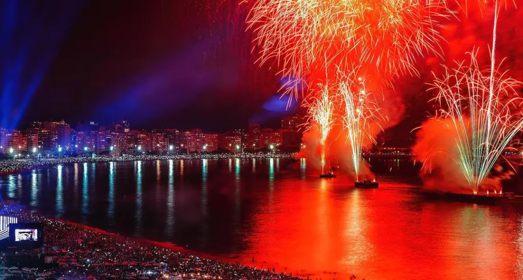 Queima de fogos em copacabana com luzes refletindo na água