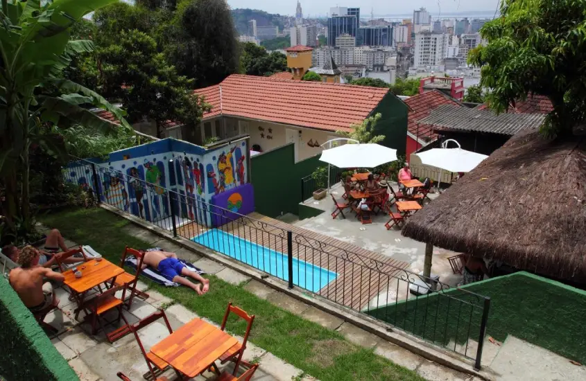 Área de lazer do Rio Forest com mesas, cadeiras, guarda-sóis, piscina e paisagem da cidade