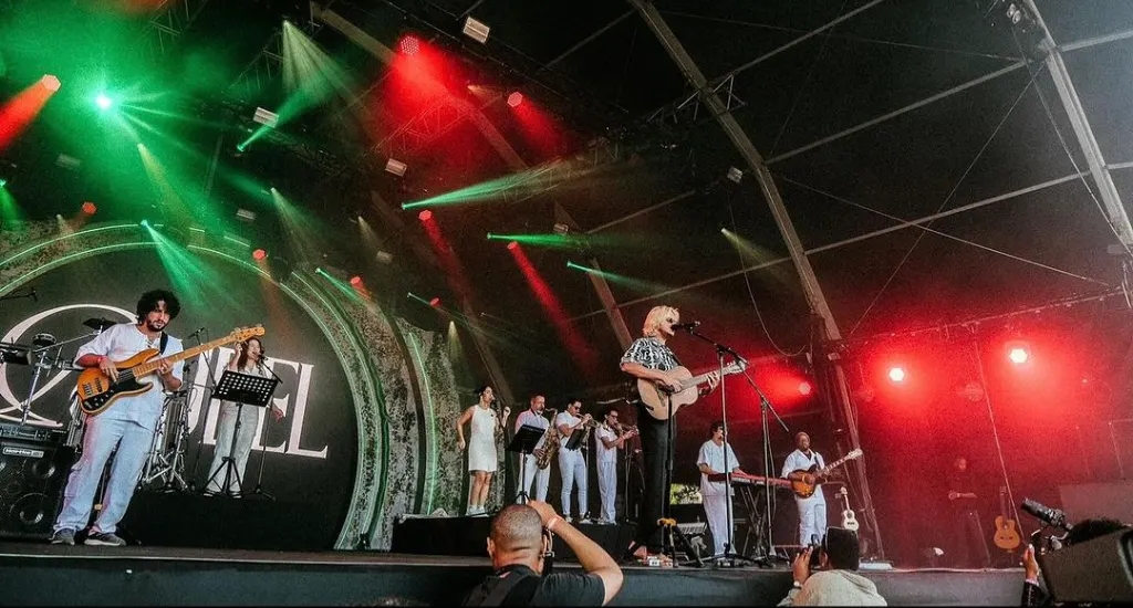 Rubel e banda tocando em um show com luzes coloridas no palco