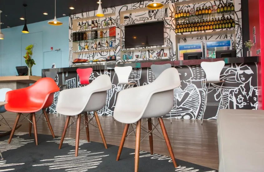 Área de bar do Ibis Rio Porto Atlântico com bancos e plantas decorativas