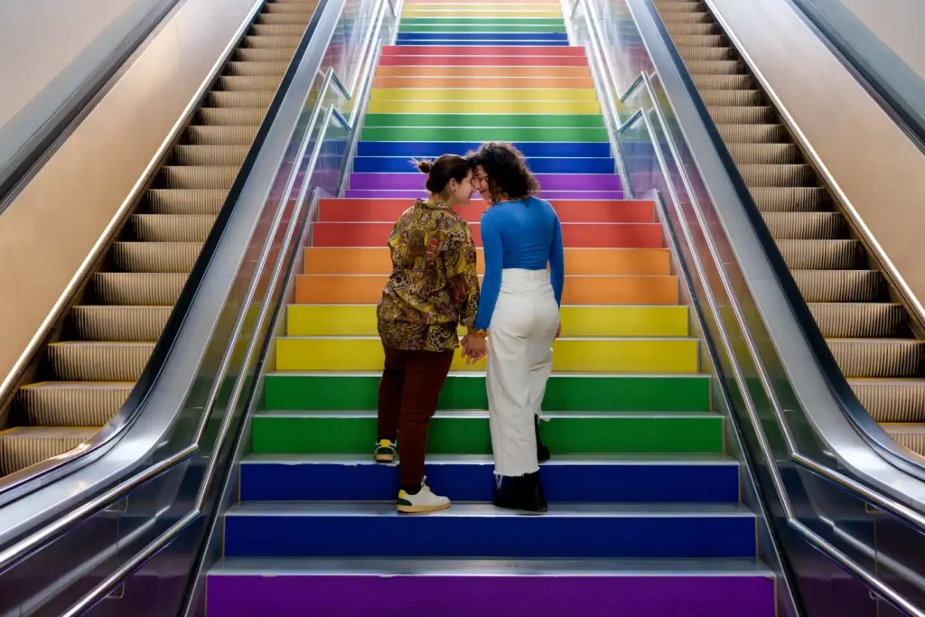 Casal lésbico subindo as escadas com a bandeira lgbt