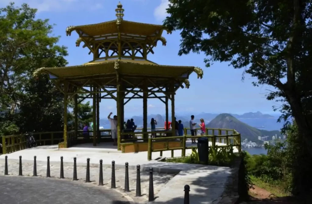 Quiosque de madeira amarelo da Vista Chinesa em um mirante, com várias pessoas apreciando a vista panorâmica da cidade e das montanhas ao fundo