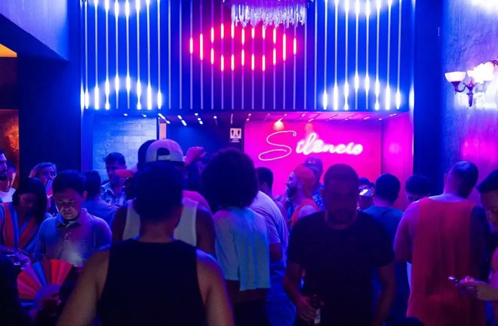 Interior do bar Silêncio Ipanema com led escrito "silêncio", pessoas e luzes coloridas ao redor