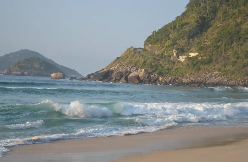 Em um dia de sol, litoral da Praia de Abricó com montanha e ilha atrás