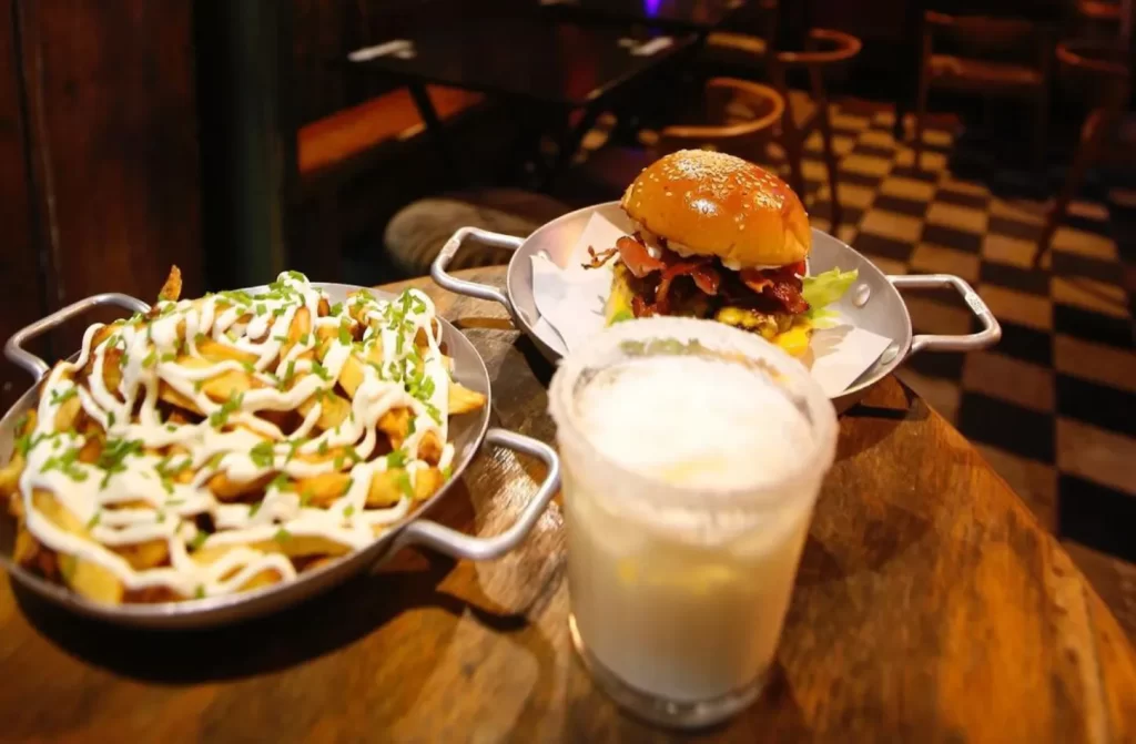 Hamburguer com batata frita e bebida com mesas, cadeiras e bancos