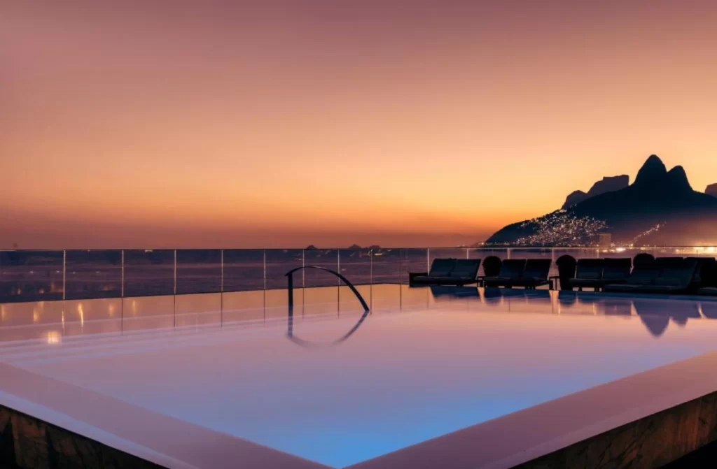 Durante um final de tarde, cobertura de um hotel com paisagem da praia e para as montanhas com piscina iluminada