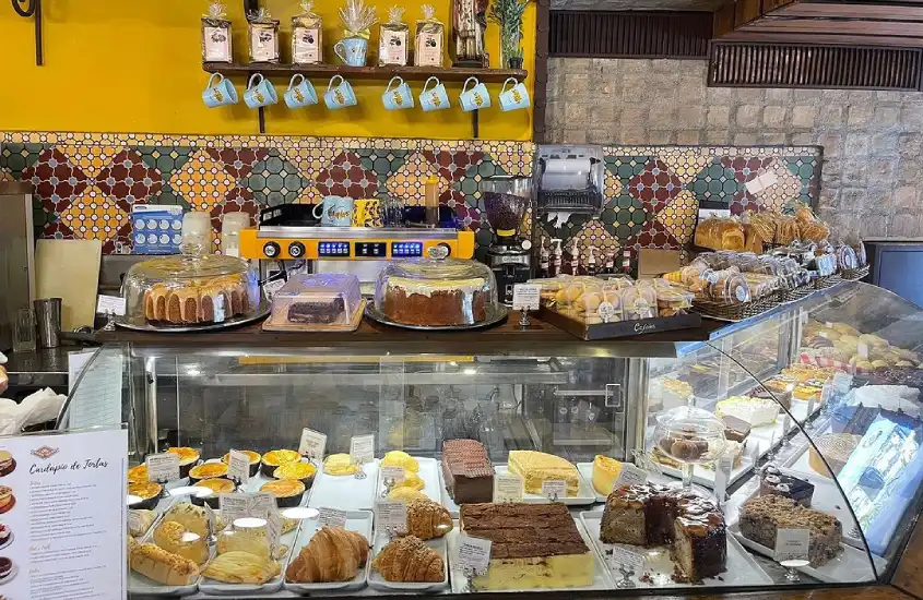 Interior da Cafeína com bolos, doces, xicaras pequenas e cafeteira