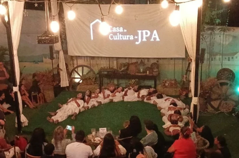 Apresentação da casa de cultura Jacarépaguá com telão branco e pessoas ao redor