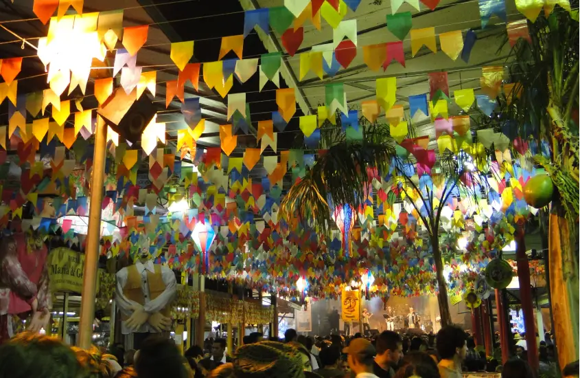 Durante a noite Centro Luiz Gonzaga de Tradições Nordestinas com bandeirinhas, árvores, luzes e pessoas circulando