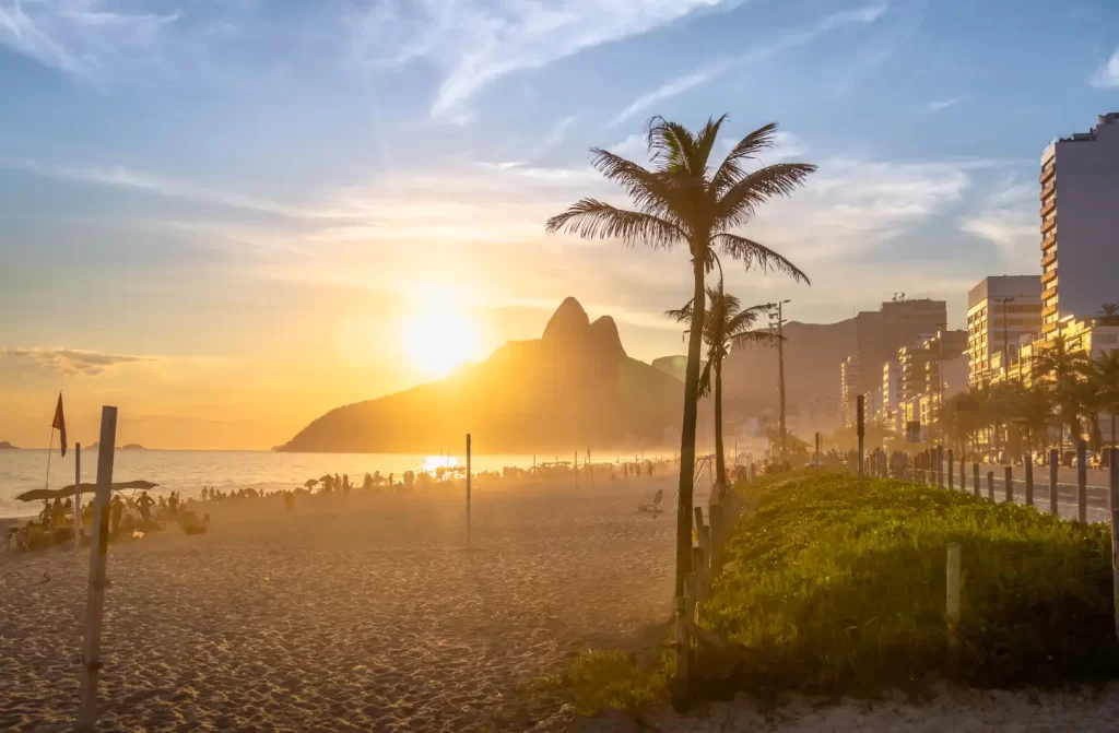 Durante o pôr do sol, paisagem da praia com árvores, pessoas e barracas ao redor