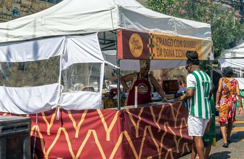 Em um dia de sol, barraquinha da Feira Yabas com pessoa comprando