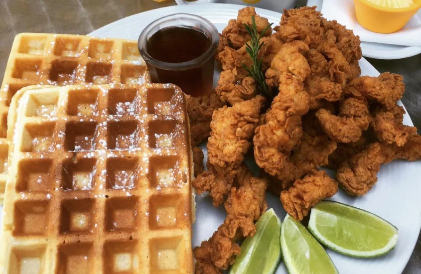 Prato do gringo café com waffles, peixe empanado, molho e limões fatiados