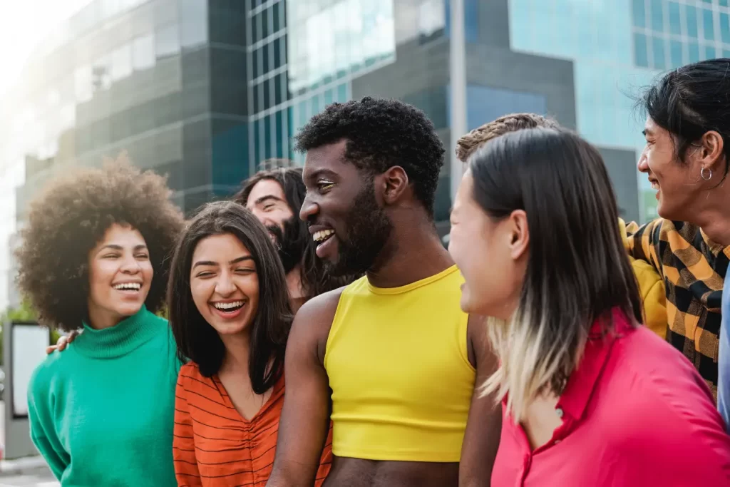 Em um dia de sol grupo de pessoas diverso rindo e conversando