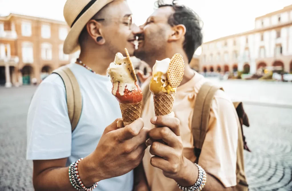 Em um dia de sol, casal gay tomando sorvete e se beijando