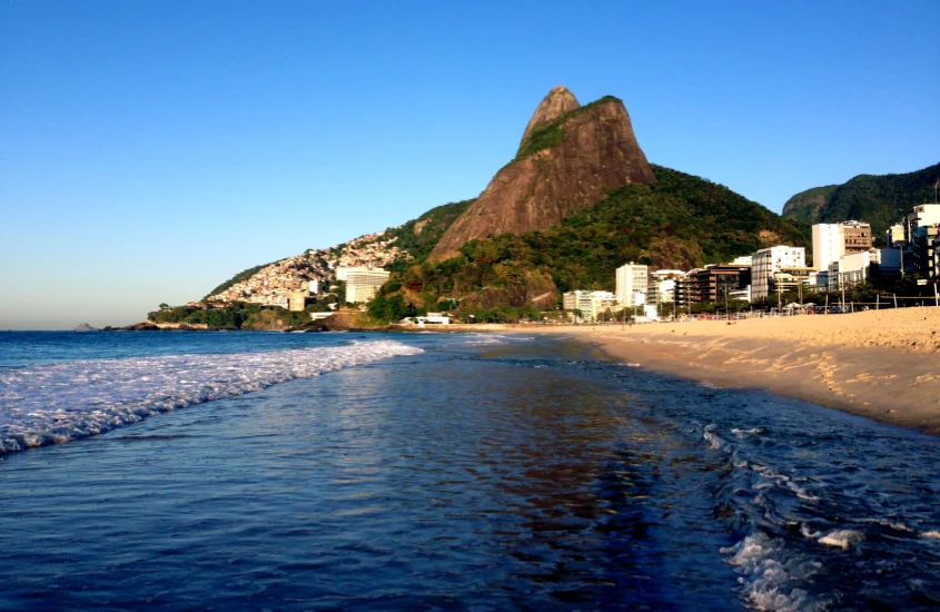 Em um dia de sol, Praia do Leblon, mar calmo e montanhas atrás