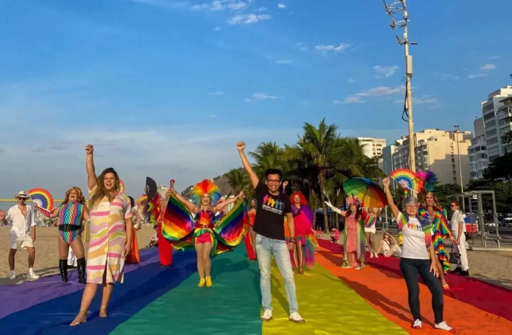 Em um dia de sol, pessoas lgbt andando em arco-íris gigante com árvores ao redor