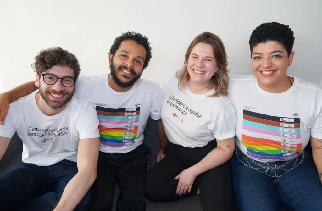 Pessoas de uma ONG de auxílio a LGBTs com camisas representativas se abraçando