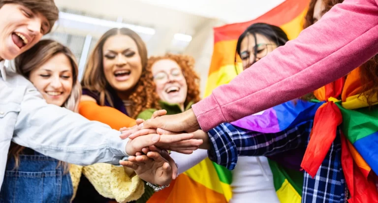 Pessoas da comunidade LGBTQIAPN+ dando as mãoes e comemorando