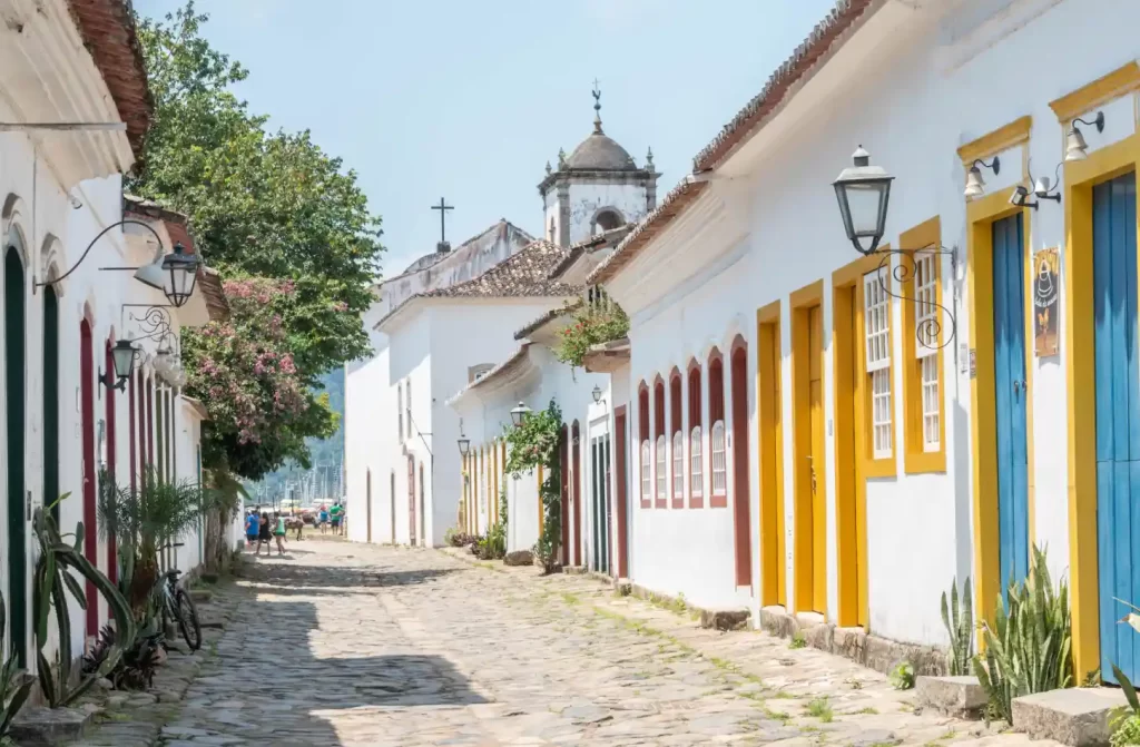 Em um dia de sol, parte histórica de uma cidade com pinturas de marcos coloridos e árvores ao redor