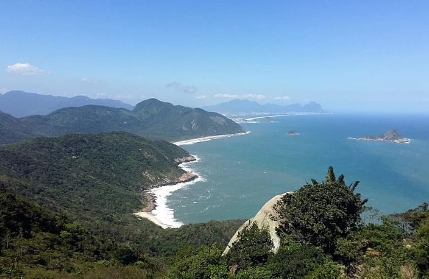 Em um dia ensolarado, paisagem da Pedra do Telégrafo com praia embaixo com montanhas ao redor