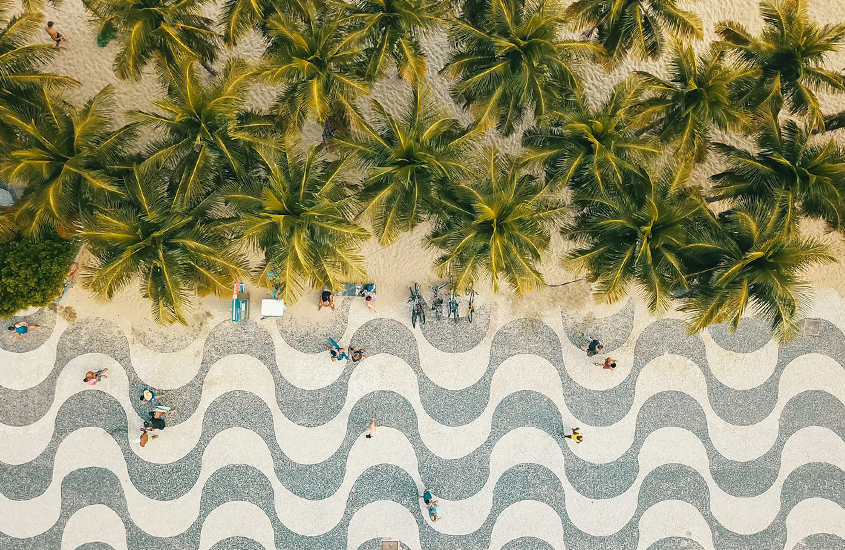 Vista aérea do calçadão com pessoas circulando e árvores na praia