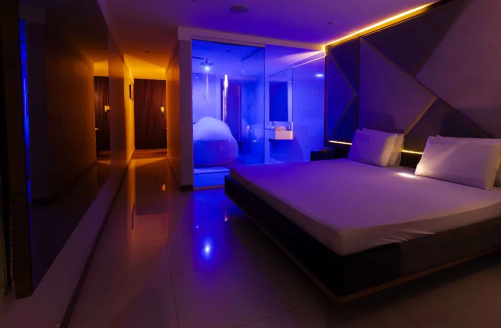 Quarto do Alphaville Hotel com luzes coloridas, cama de casal e banheira de hidromassagem