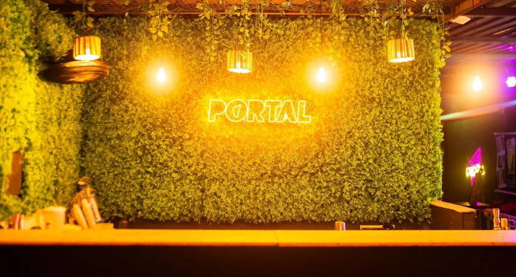 Painel de plantas com letreiro "portal" iluminado por luzes amarelas